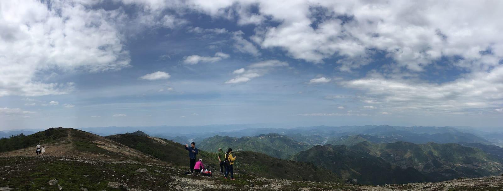 Hikers on a ridge trail above the layered green mountains of Tiantai, Zhejiang