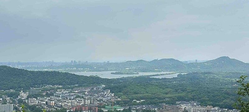 Panoramic view of West Lake from the Majiawu viewing platform with the city skyline beyond