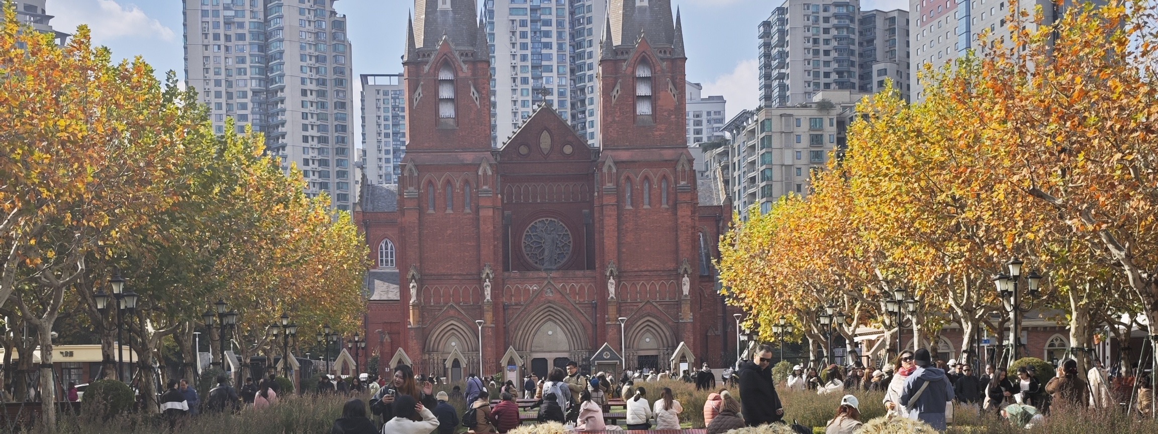 Photograph of the twin-spired St Ignatius Cathedral framed by autumn plane trees in Xujiahui